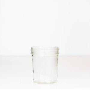 Wide mouth half pint mason jar with straight sides and measurement markings against a white background 