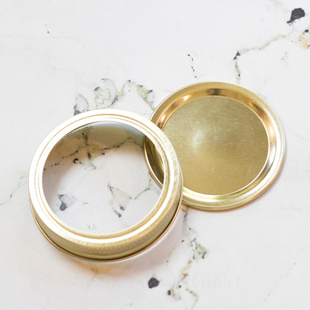 Plain Gold Regular Mouth (Standard) Mason Jar Lid and Ring, shown on a marble background.